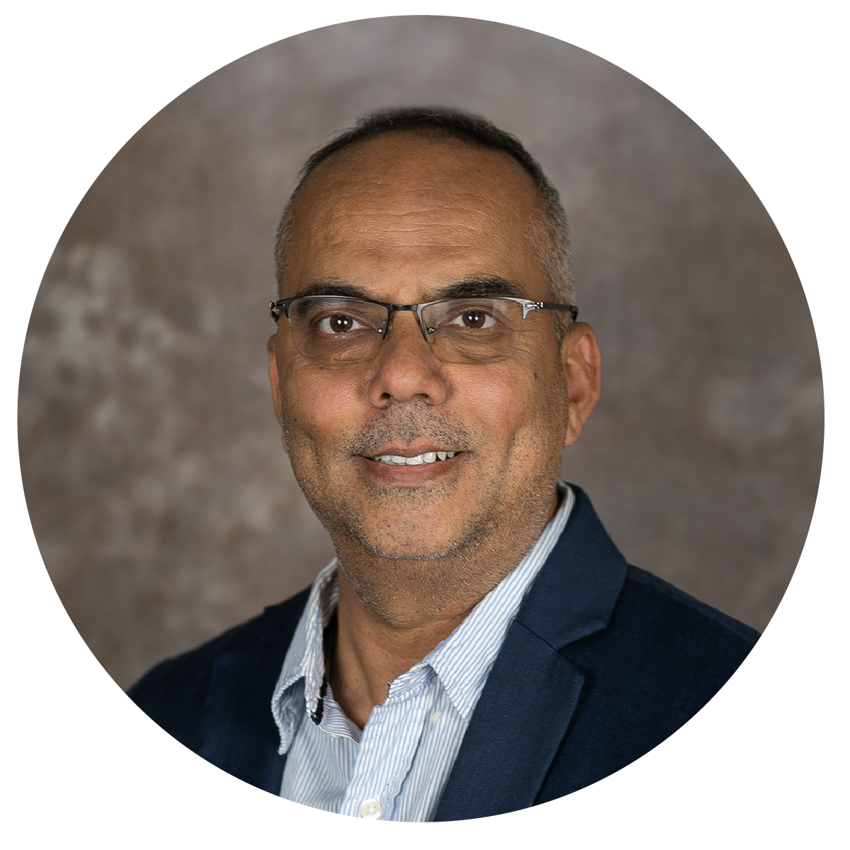 Professional headshot of a middle-aged man with glasses, wearing a navy blazer and a light blue collared shirt, smiling at the camera against a neutral background.