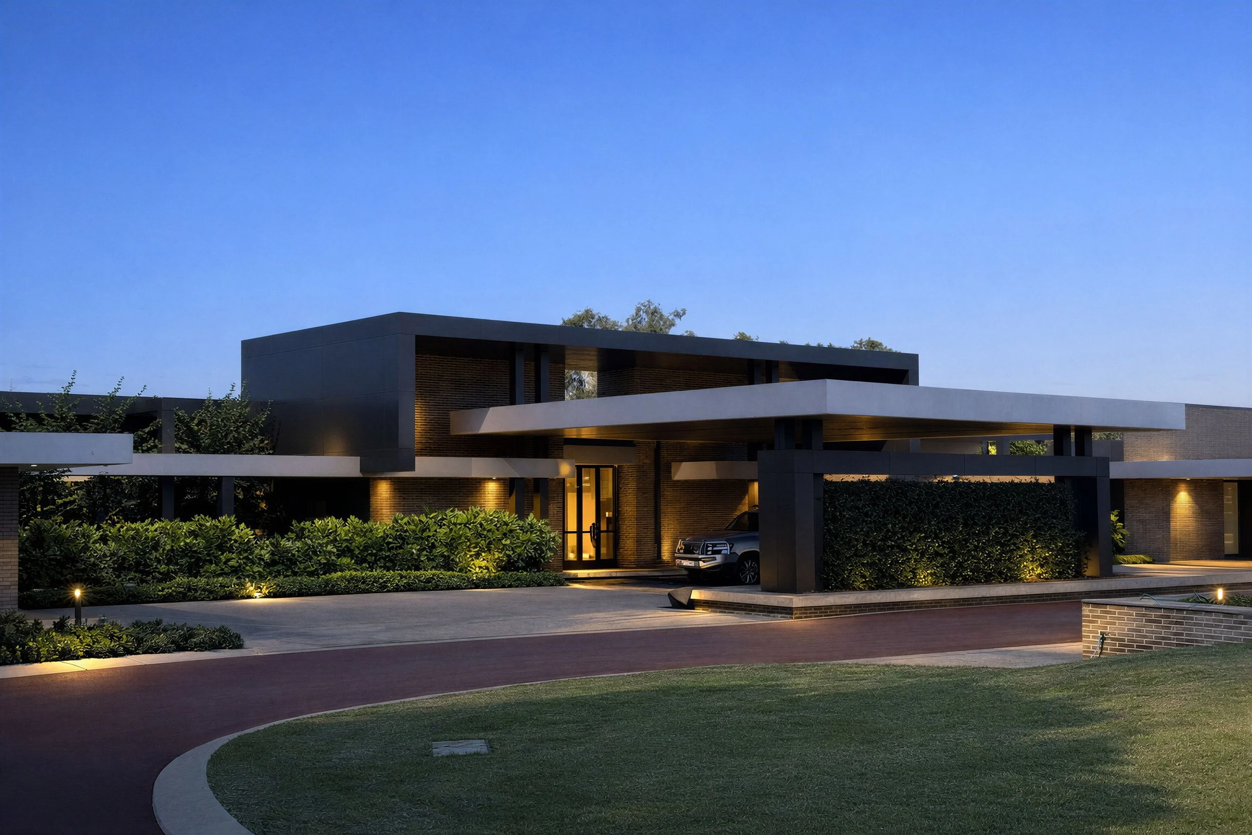 Modern house with clean lines, illuminated at dusk, with a driveway, landscaping, and a car parked in the garage.
