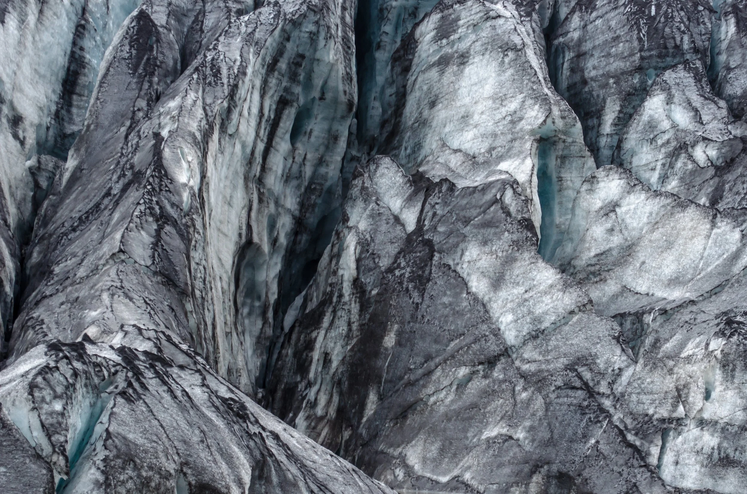 Close-up of a glacier with blue ice and cracked gray and white ice formations.