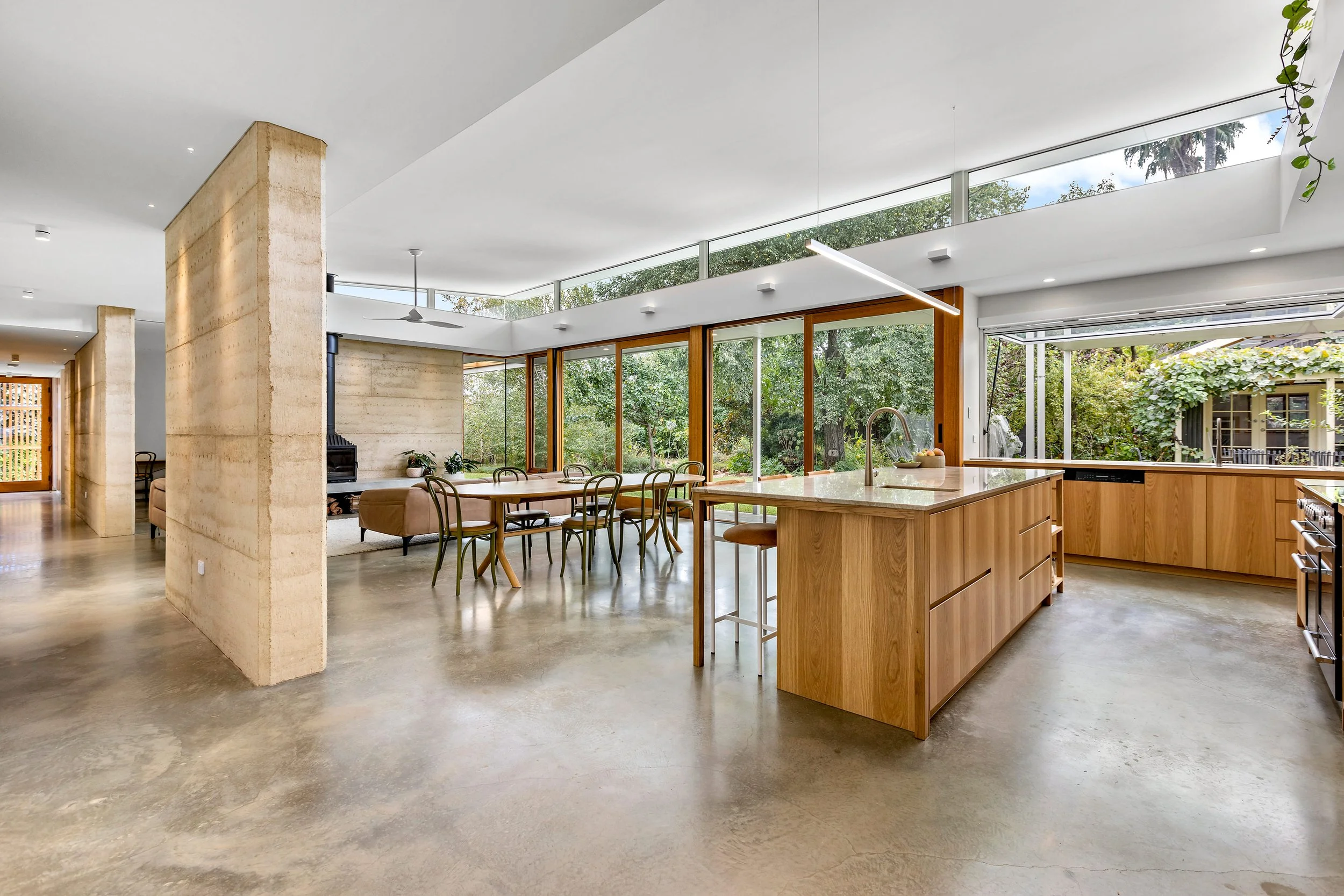 Open-concept kitchen and dining area in a modern home with large windows, minimalist design, and natural light.
