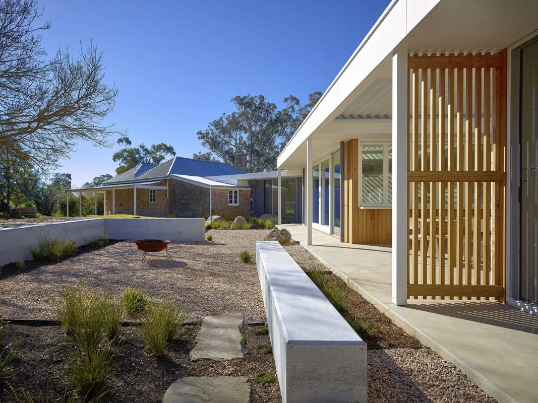 Modern house with a patio, wooden slatted privacy screen, and garden area with gravel and plants.
