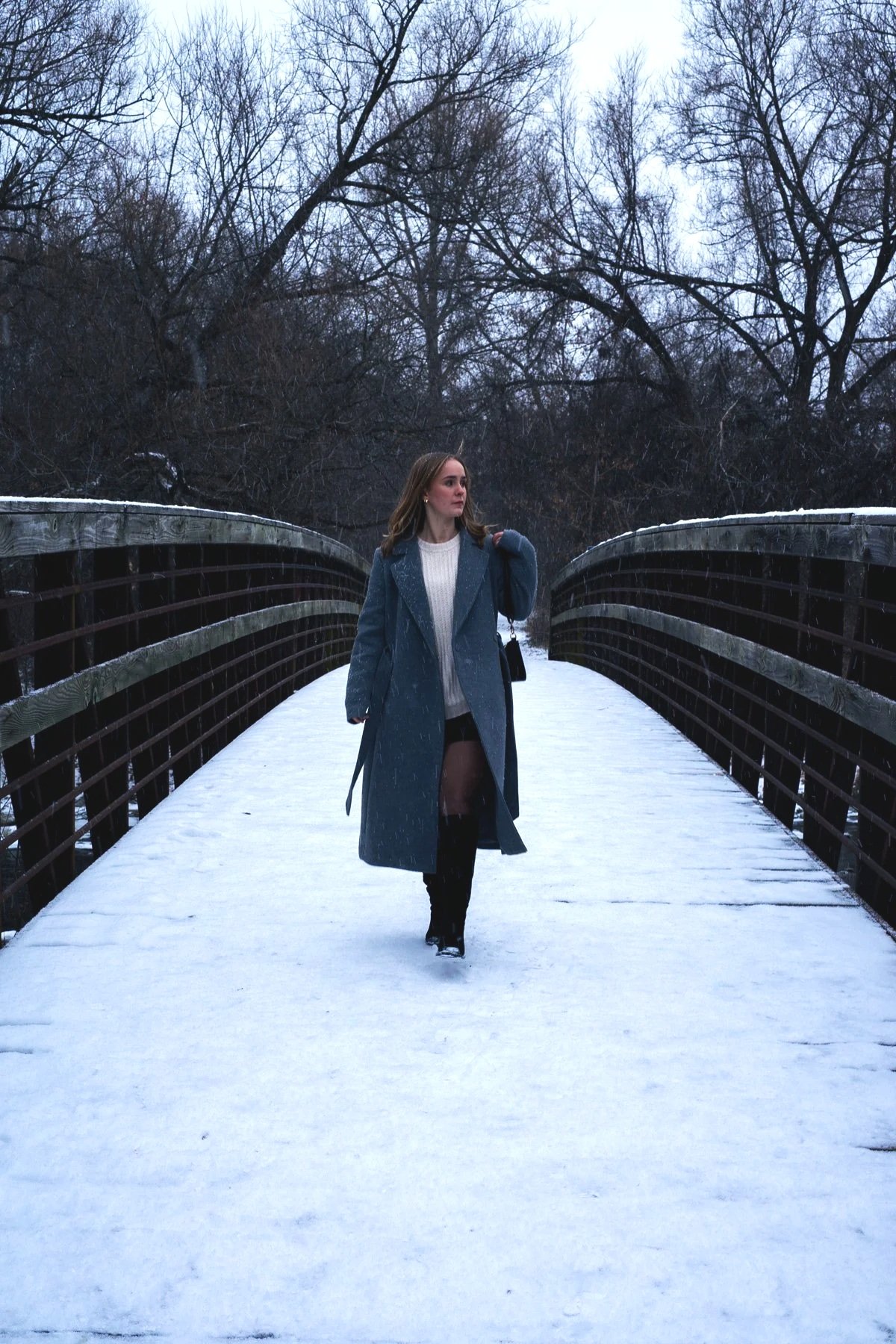 Abigail Flipsen standing on a wooden bridge in the Humber Arboretum during a winter documentary session.