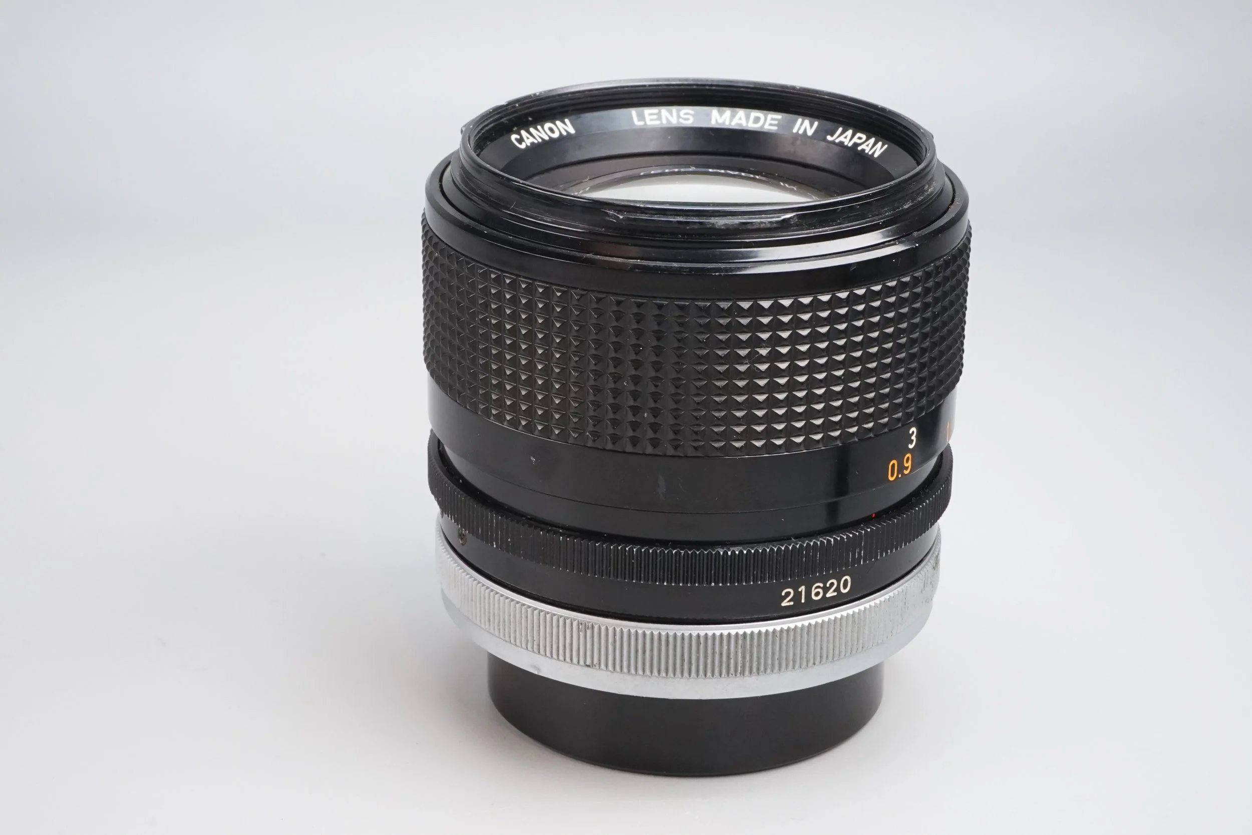 カメラレンズのアップ写真。黒色で、焦点距離は0.9から3まで示し、銀色のリングも付いている。