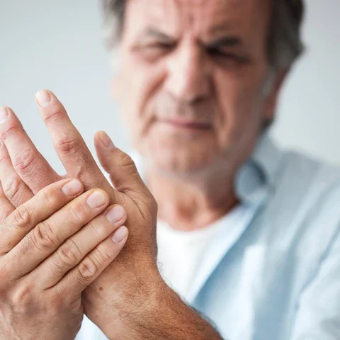 Older man holding his wrist in pain, grimacing with discomfort due to join pain.