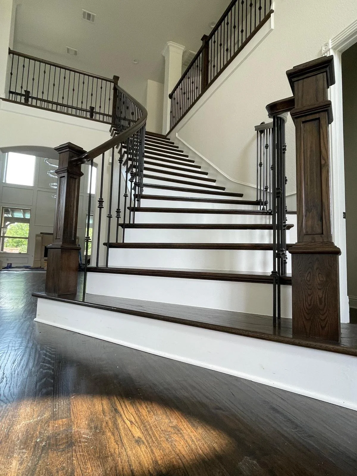 Interior view of a curved staircase with dark wood handrails and light-colored risers, leading to an upper floor in a modern home.