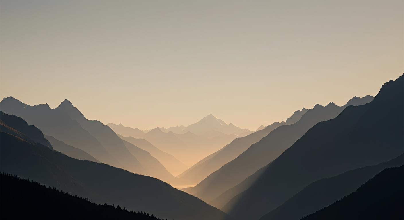A panoramic view of mountain ranges with layers of peaks fading into the distance during sunset or sunrise.