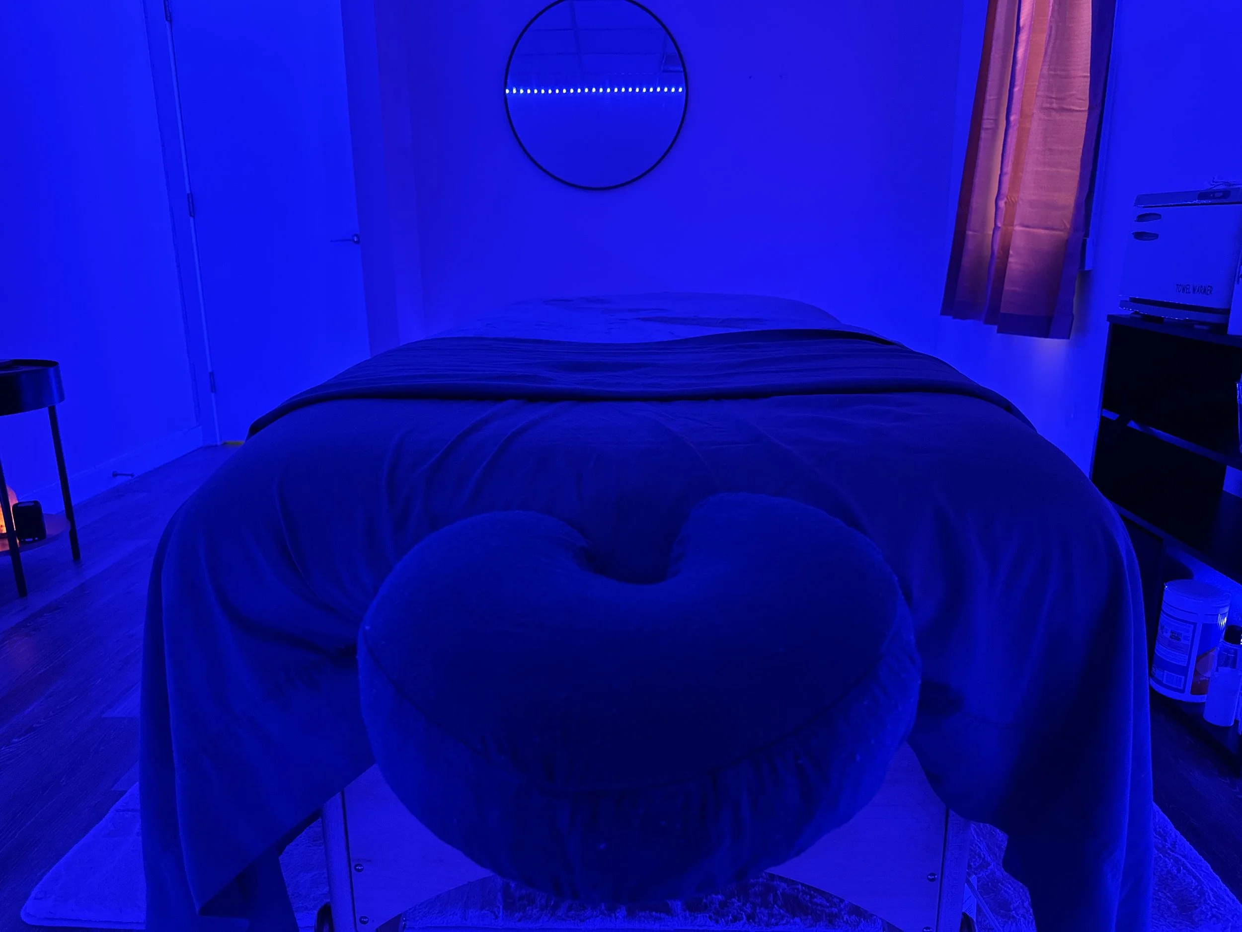 A massage room with blue relaxing lights and a massage table