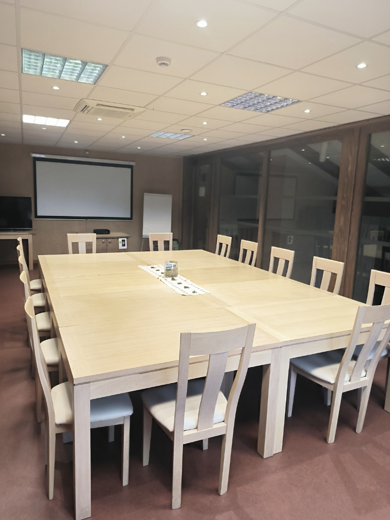 Salle de réunion pour des séminaires ou autres rassemblement d'entreprises avec tables, écran télé, vidéoprojecteur