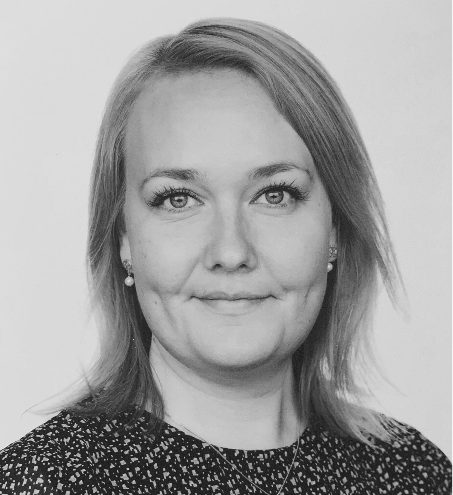 Sort-hvid college-portræt af en kvinde med lyst, skulderlangt hår, iført øreringe og sort kjole med hvide mønstre.