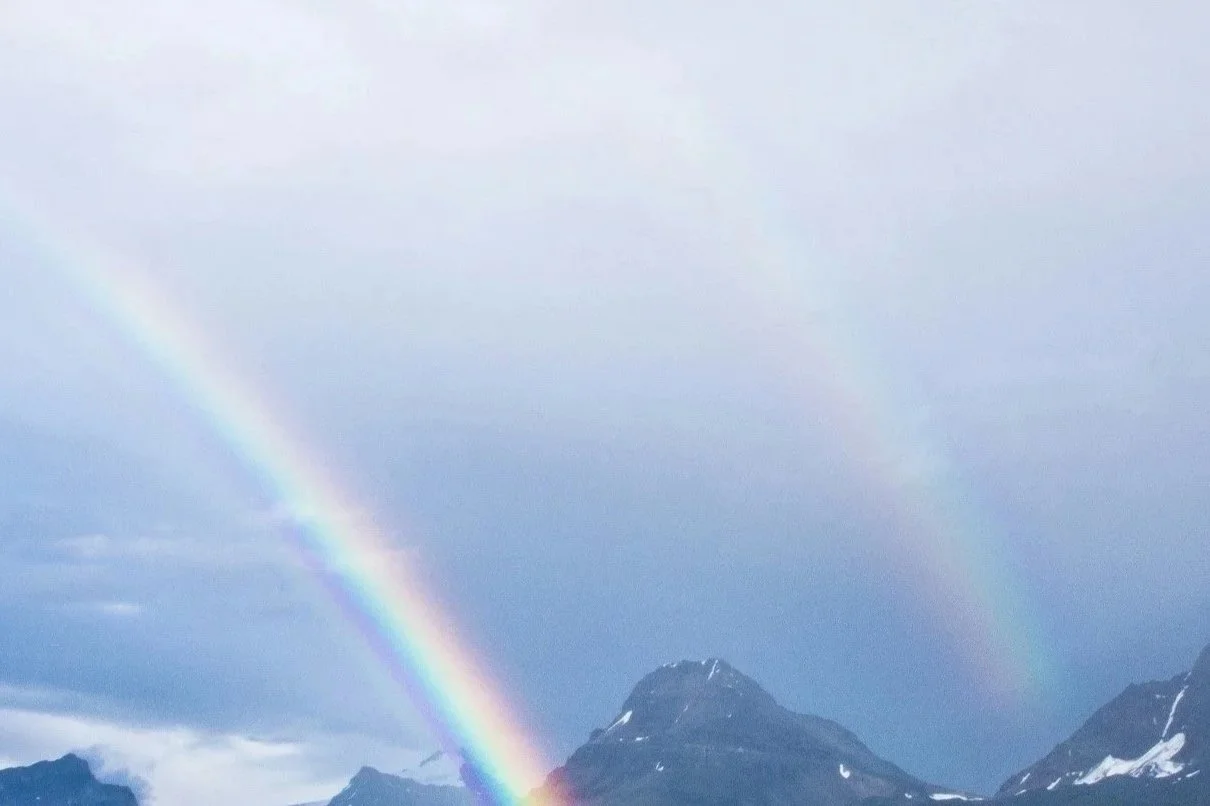 Regnbågar över snötäckta berg.