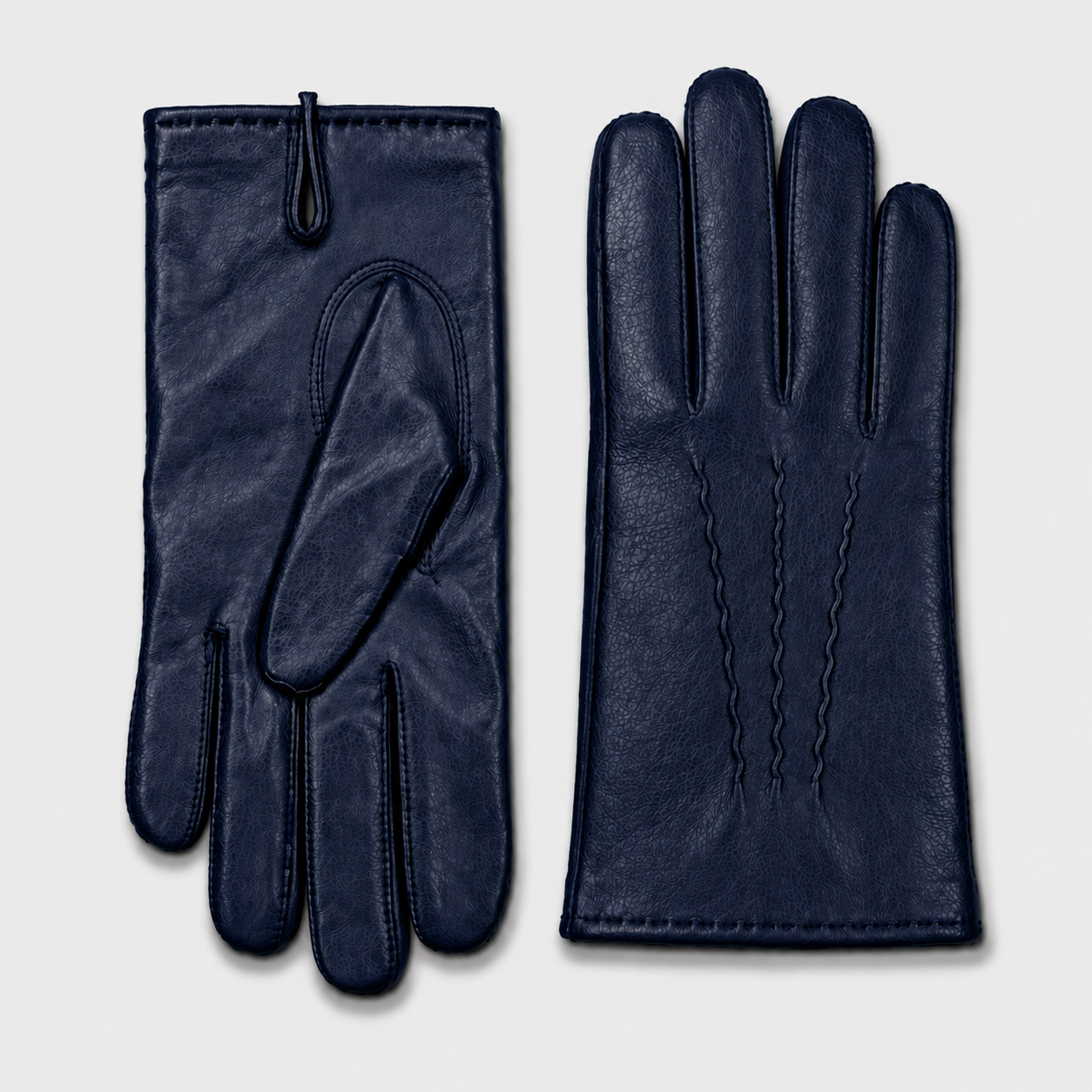 Une paire de gants en cuir bleu foncé avec une texture tachetée sur une surface blanche.