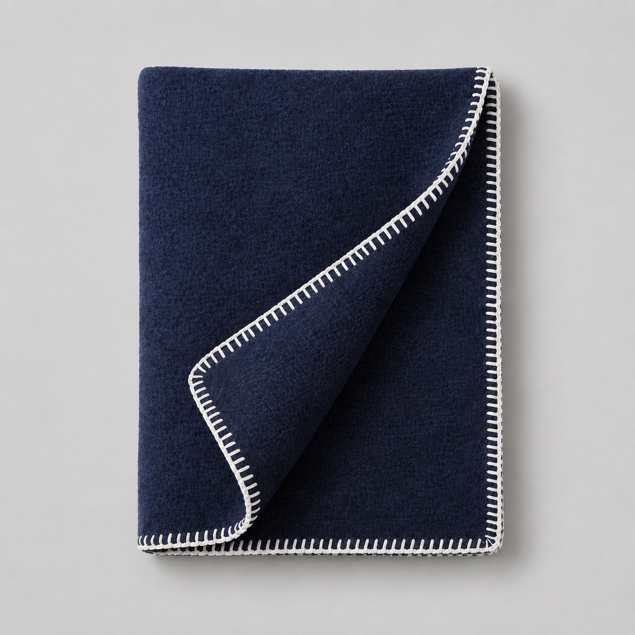 Serviette de bain bleue avec bordures blanches, repliée sur un fond gris clair.