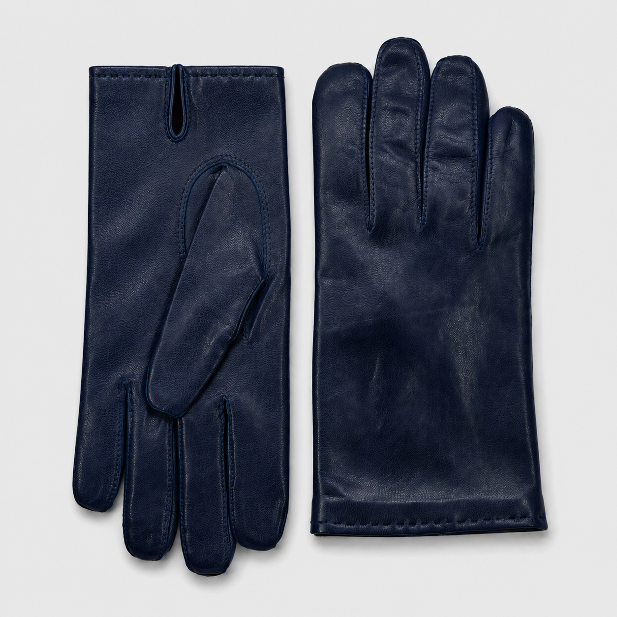 Une paire de gants en cuir bleu foncé posés sur un fond blanc.