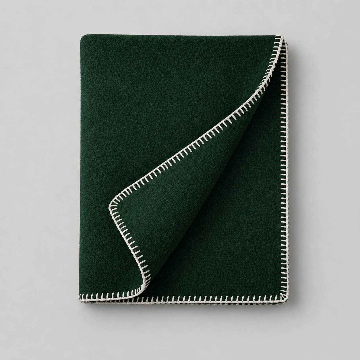 Un tapis vert avec des bords cousus en blanc posé sur un fond gris