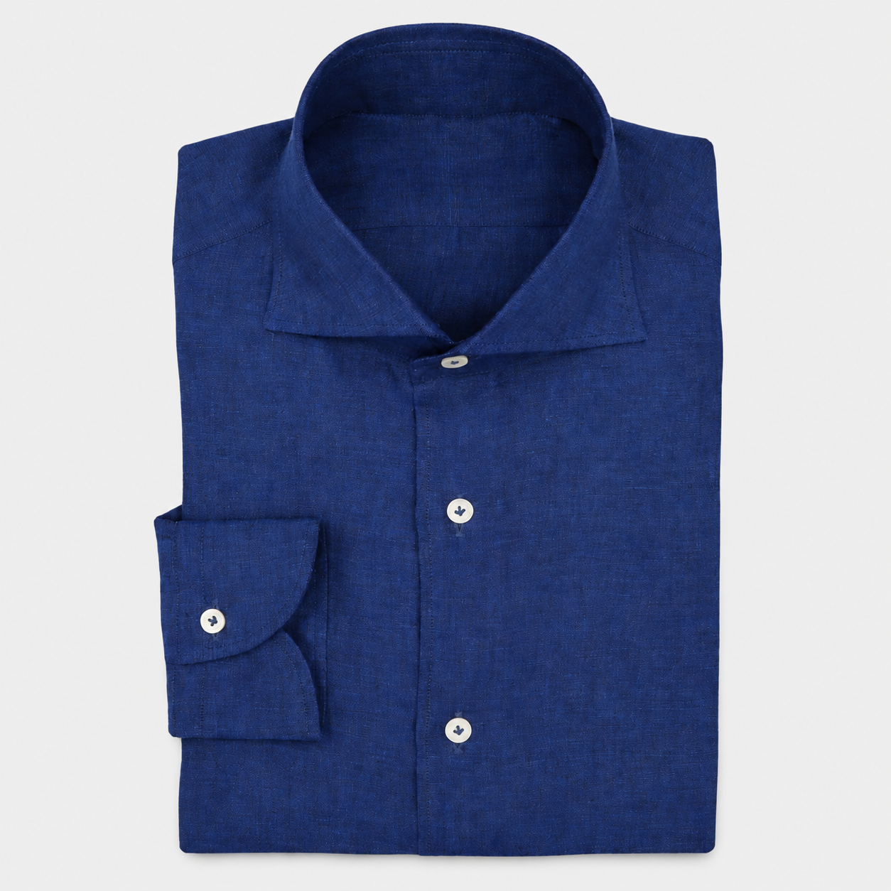 Chemise en lin bleu pliée, boutons visibles, manches repliées