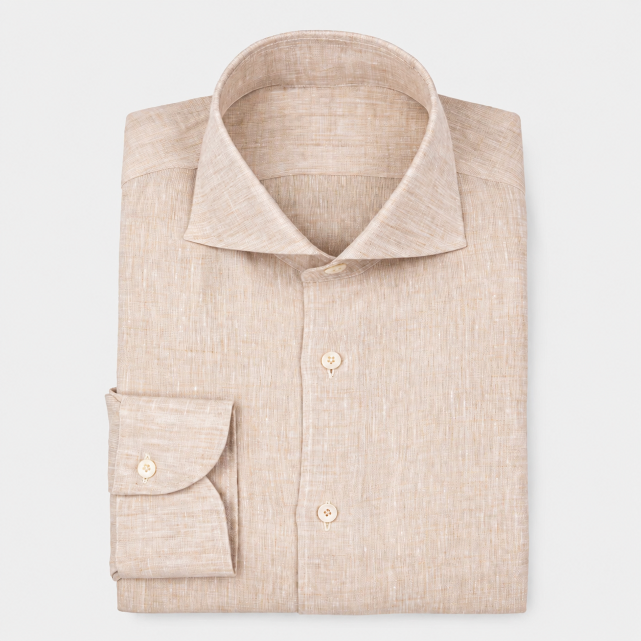 Chemise beige en lin avec col classique et boutons devant, manches longues avec boutonnière, pliée sur fond blanc.
