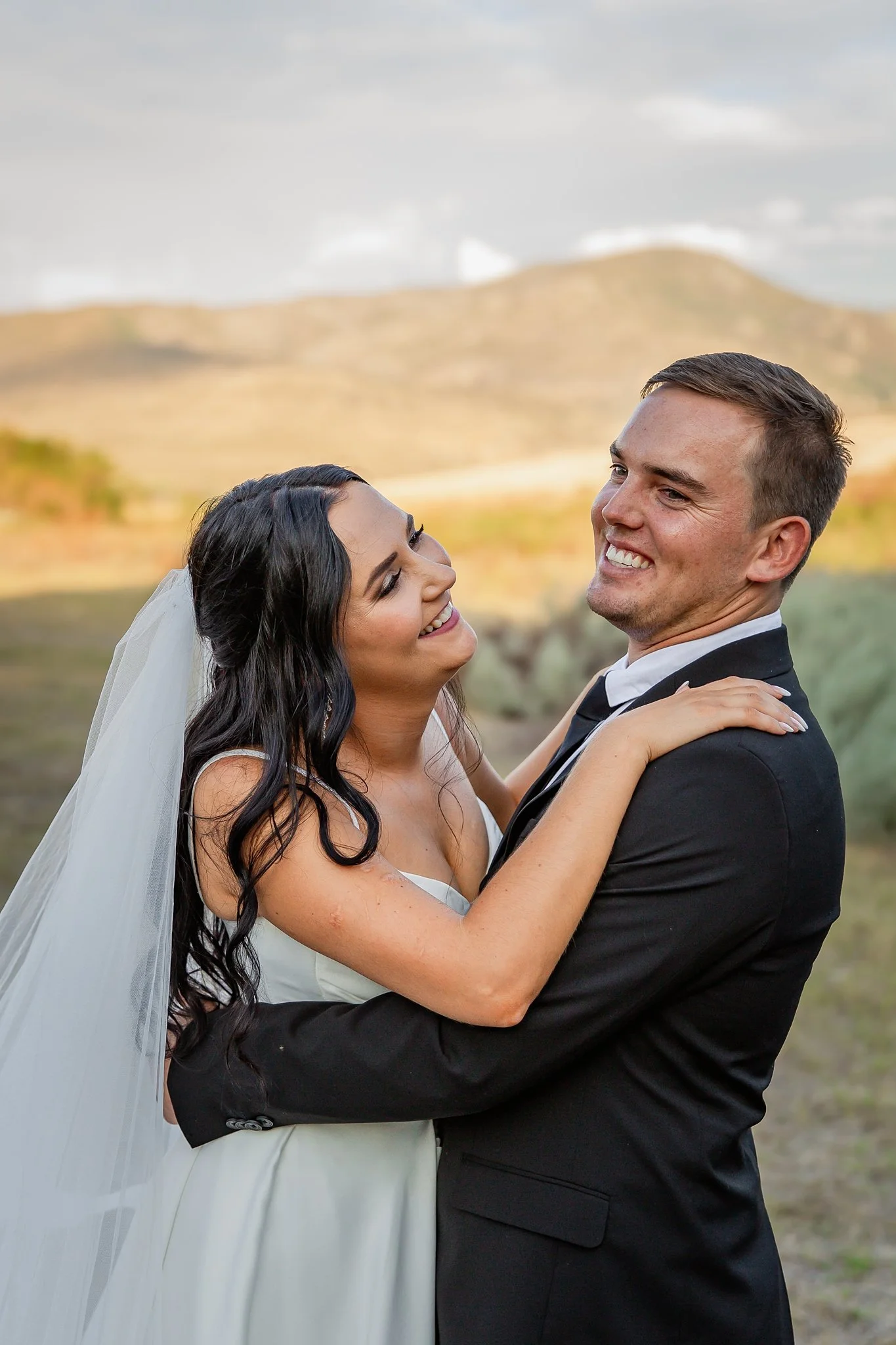 bride and groom embracing and laughing.