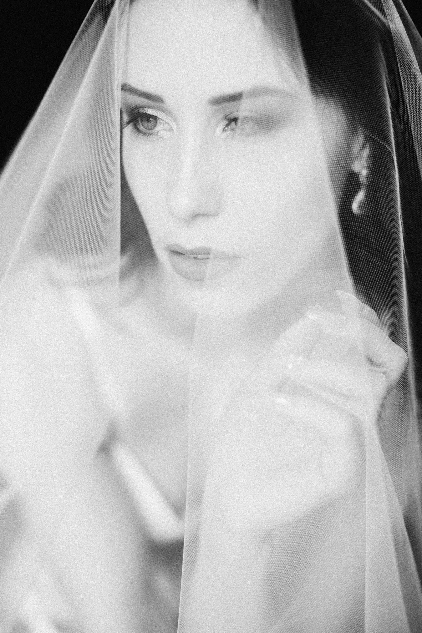 Une femme portant un voile de mariée, regardant de côté, en noir et blanc.