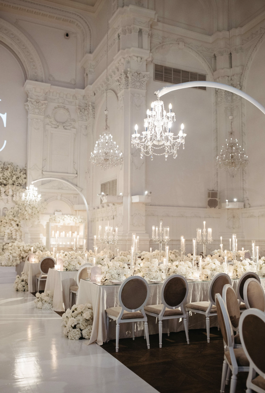 Salle de réception élégante à la Maison Principale à Montréal décorée en blanc avec chandeliers et fleurs pour un événement formel, probablement un mariage.
