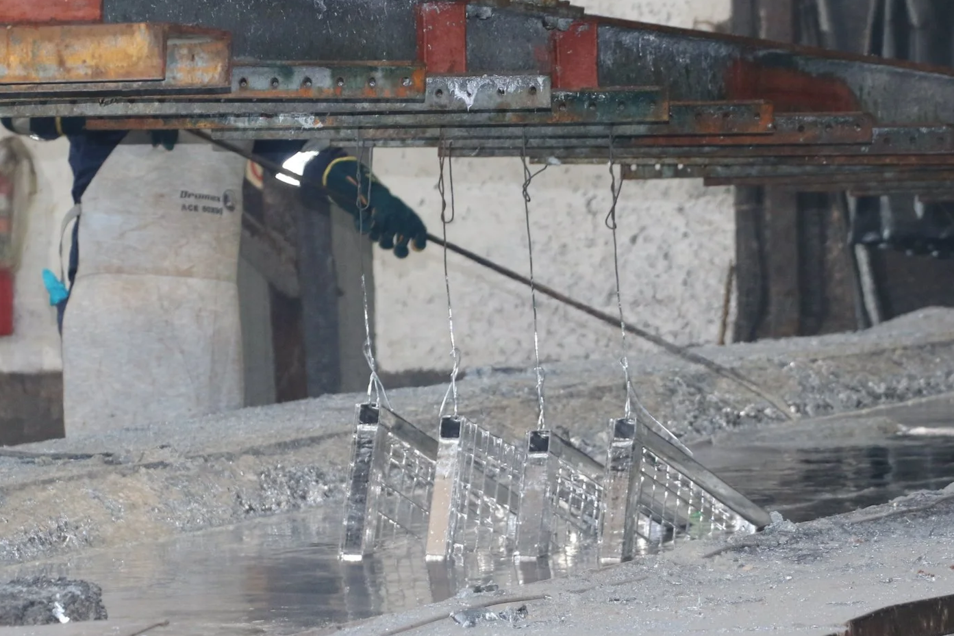 A worker in protective gear, galzinising steel for a padel court.