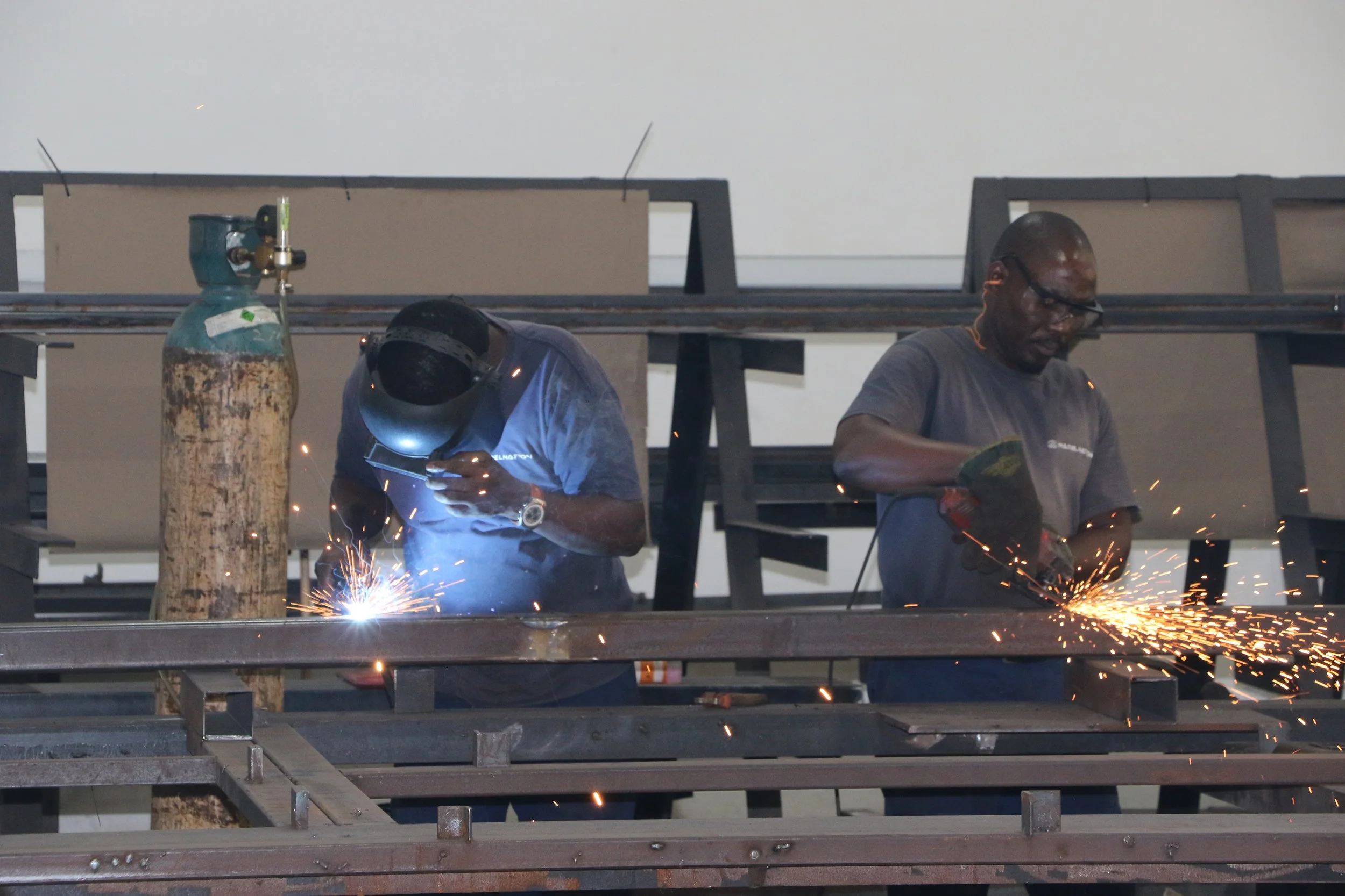 Two men welding metal on a construction site.
