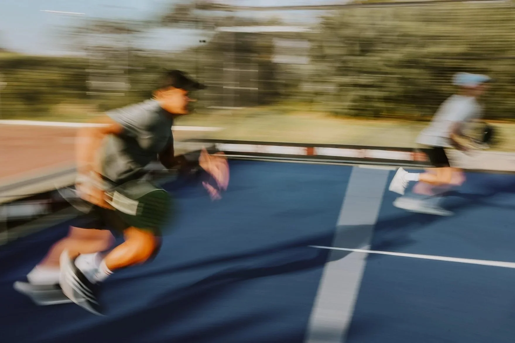 two men running towards a padel ball on a padel court.