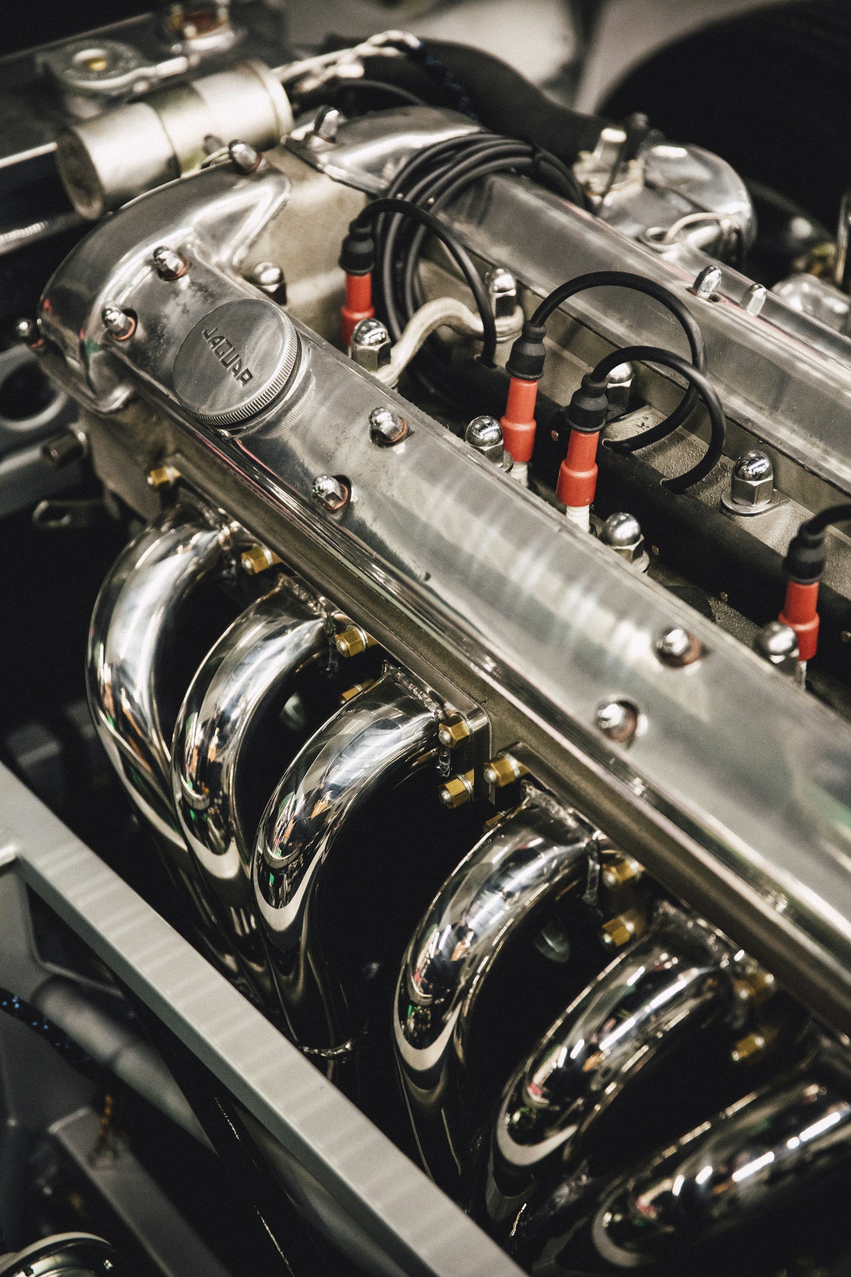 Close-up view of a high-performance car engine with polished metal components and red spark plug wires.