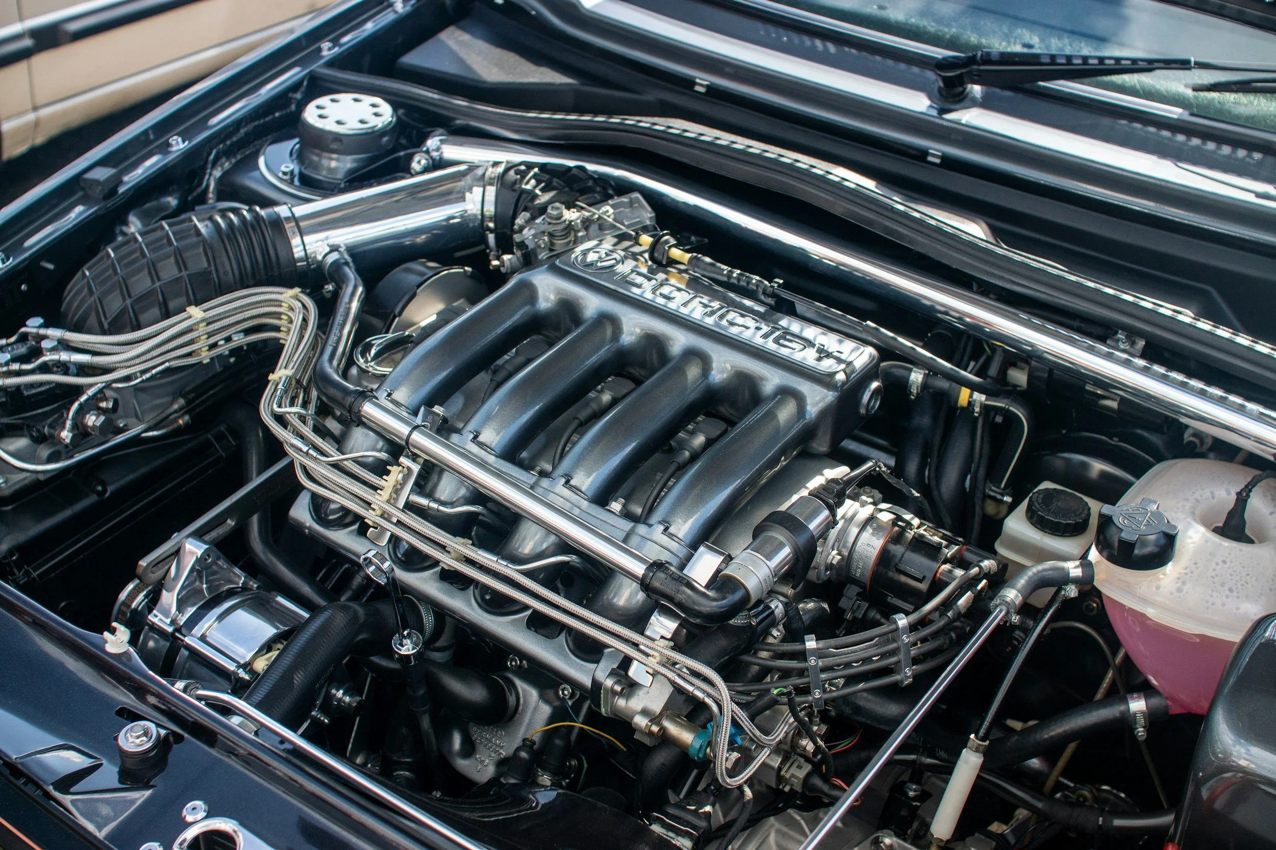 Close-up of a high-performance car engine with polished metal parts and black hoses.