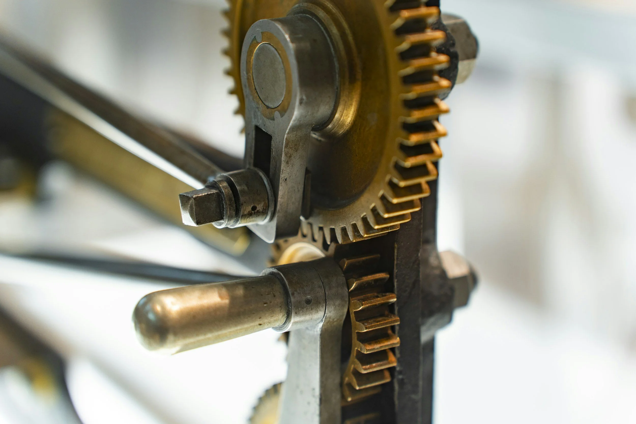 Close-up of metal gears and mechanical components in a machine, showing a large gear with teeth and a metal rod or shaft.