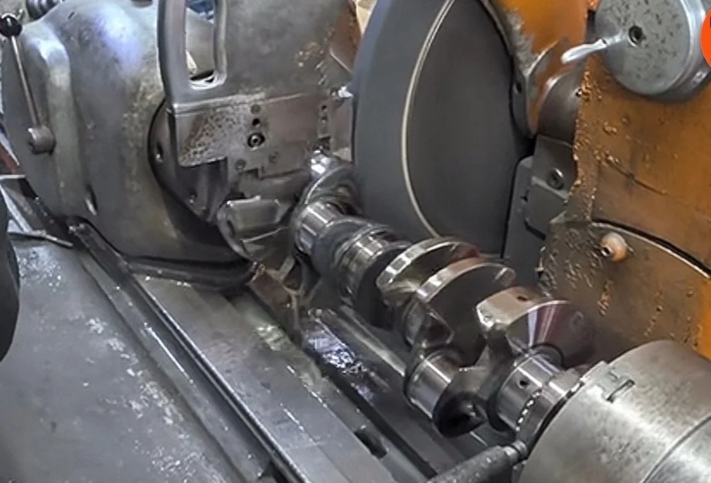 Close-up of a metal crankshaft being machined on a lathe machine.
