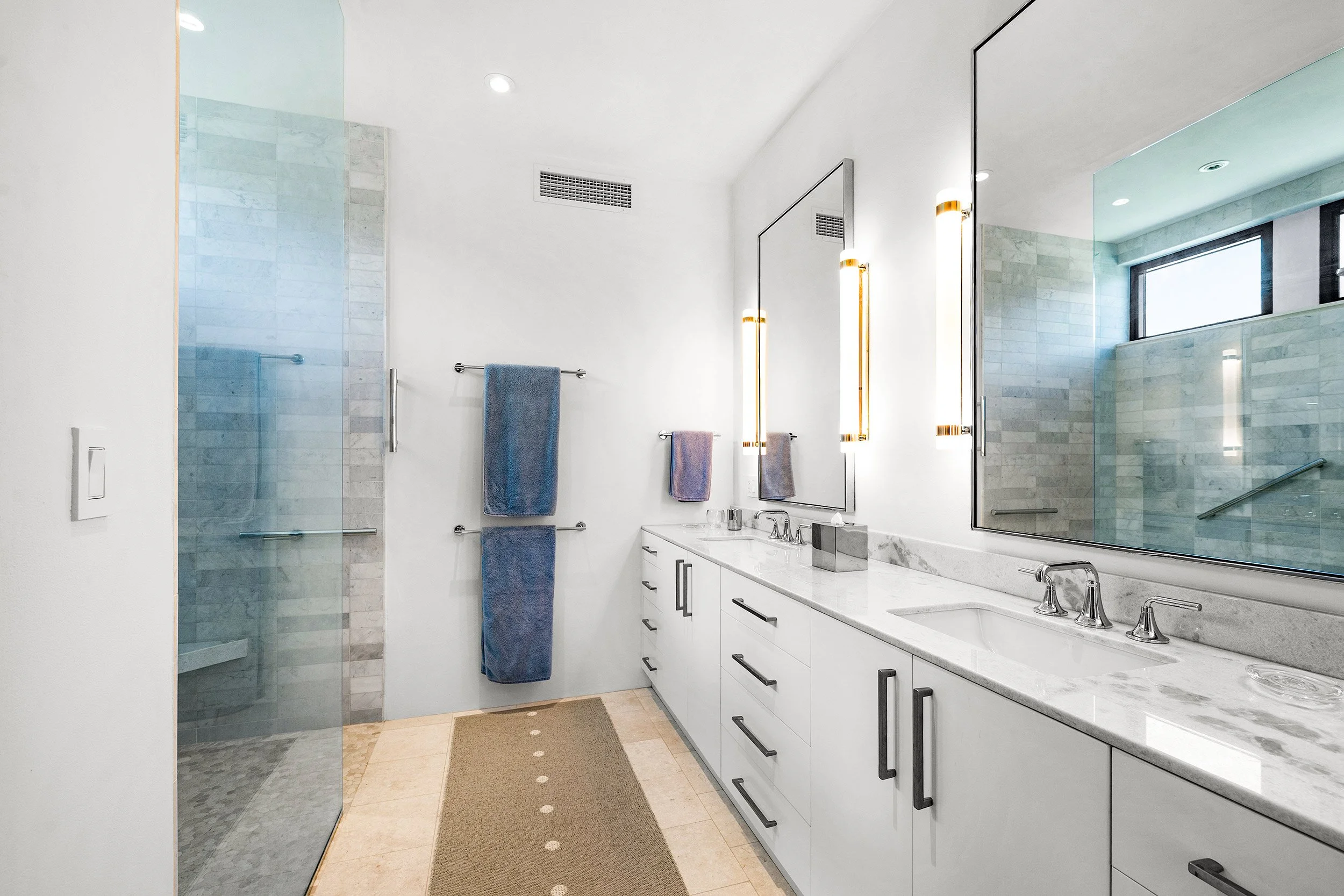 Modern bathroom with a white vanity, marble countertop, large mirror, and fixtures, a glass-enclosed shower, and a window