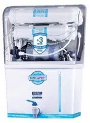 A white King Super Deluxe home water purifier with a transparent top showing internal components, and a blue and white logo. It has a tap and a water outlet at the bottom.
