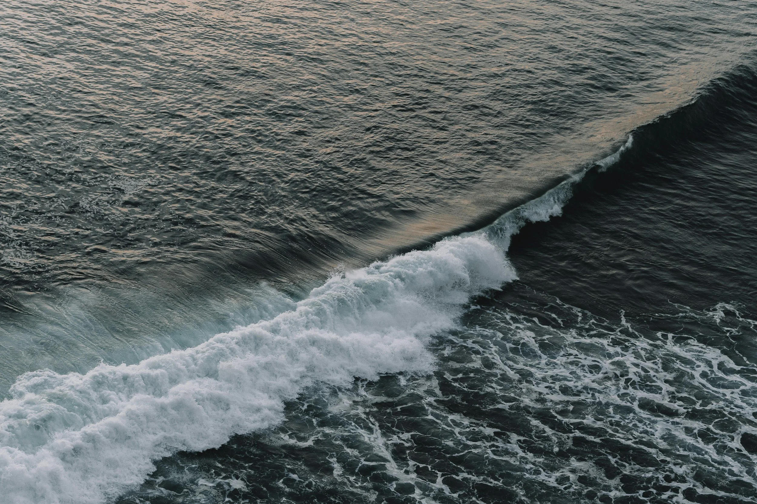 A section of the ocean showing waves and ripples with some white foam near the bottom right.