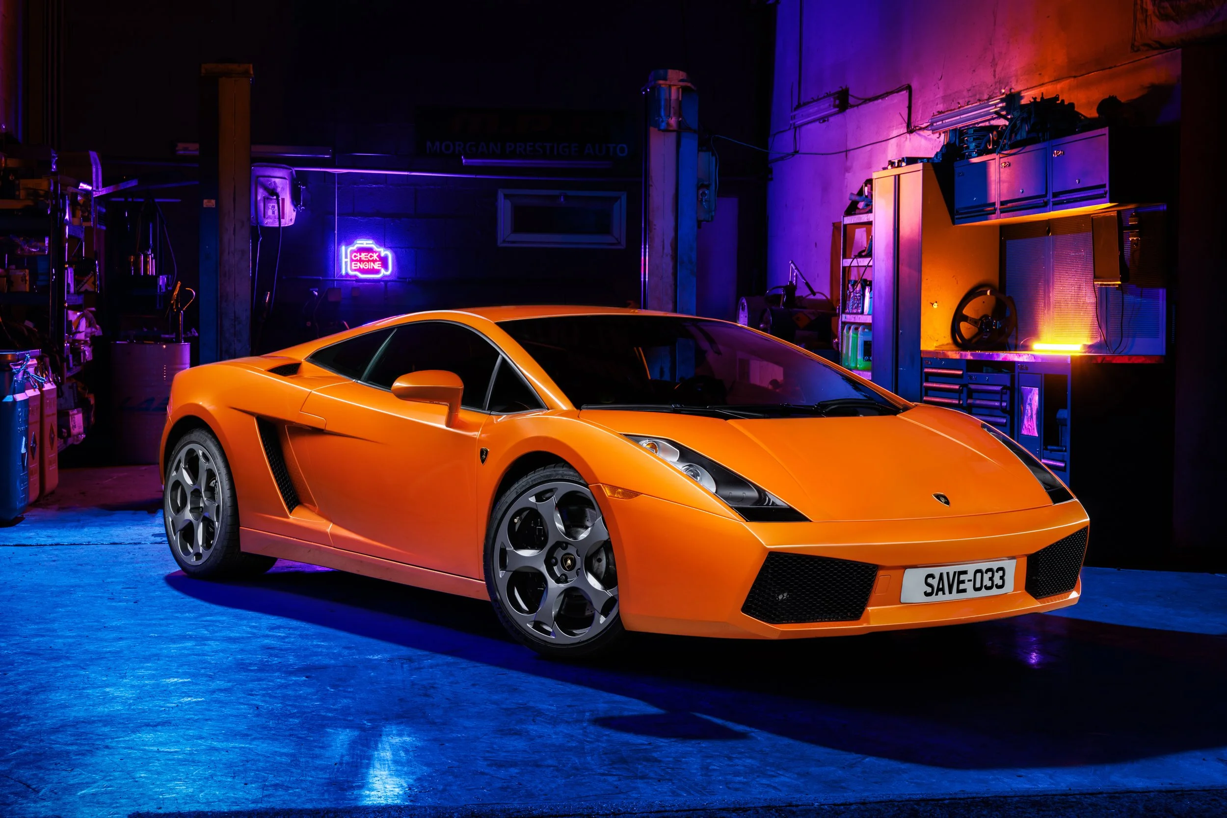Une voiture de sport orange dans un atelier avec un éclairage néon violet et orange.