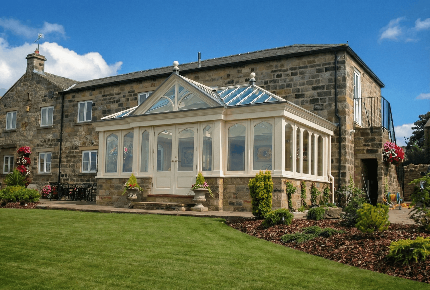 Painted timber conservatory with pointed arched glazing attached to a stone period house