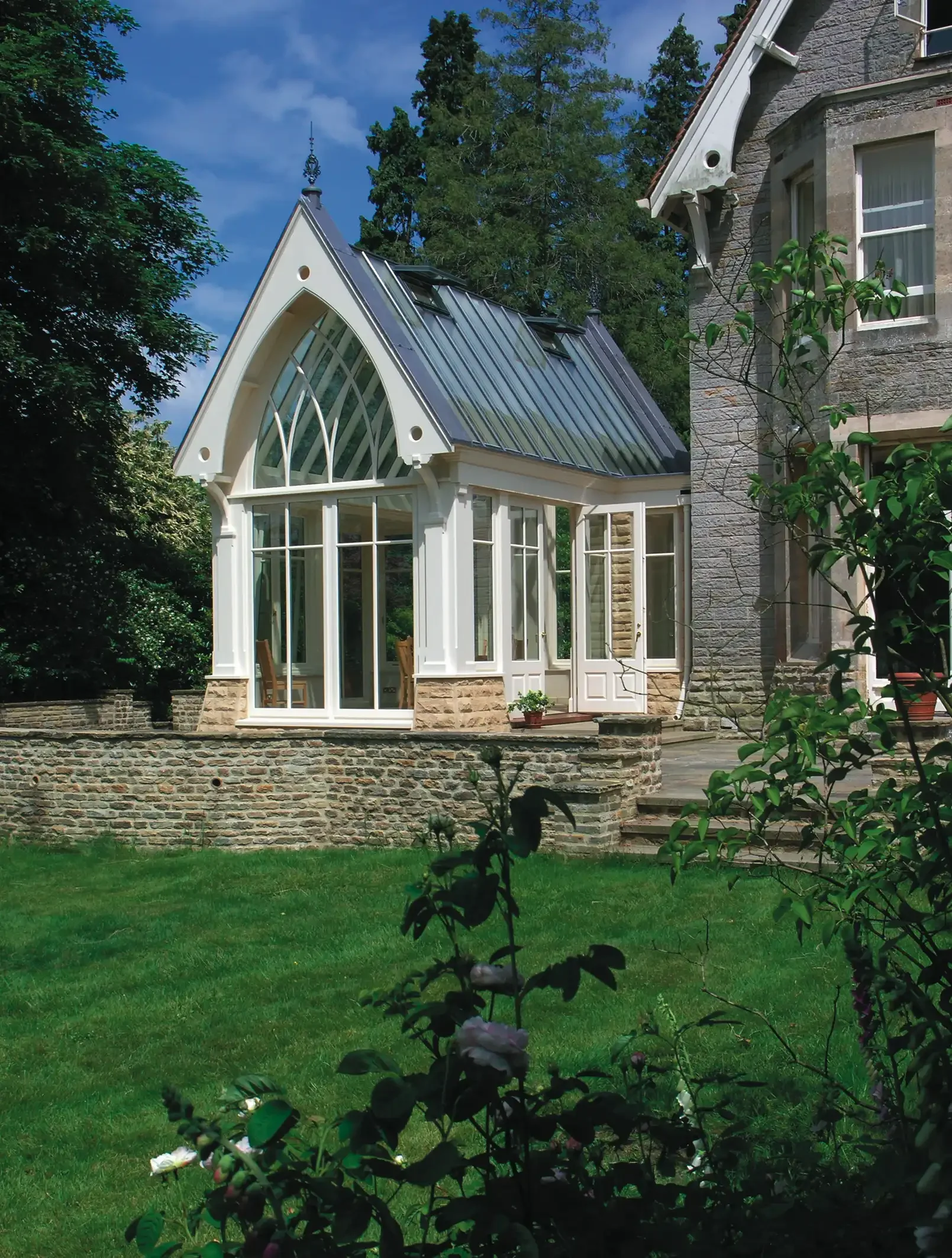 High-pitched Gothic gable end with timber tracery windows and a lead roof design.
