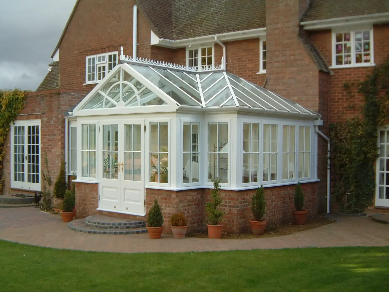 A hardwood conservatory extension with a fully glazed pitched roof built on a brick base in Salcombe, Devon.