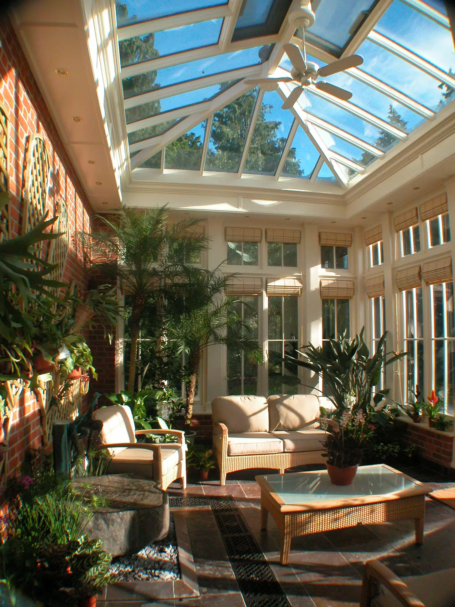 Interior of a timber conservatory with glazed roof, garden seating and mature plants