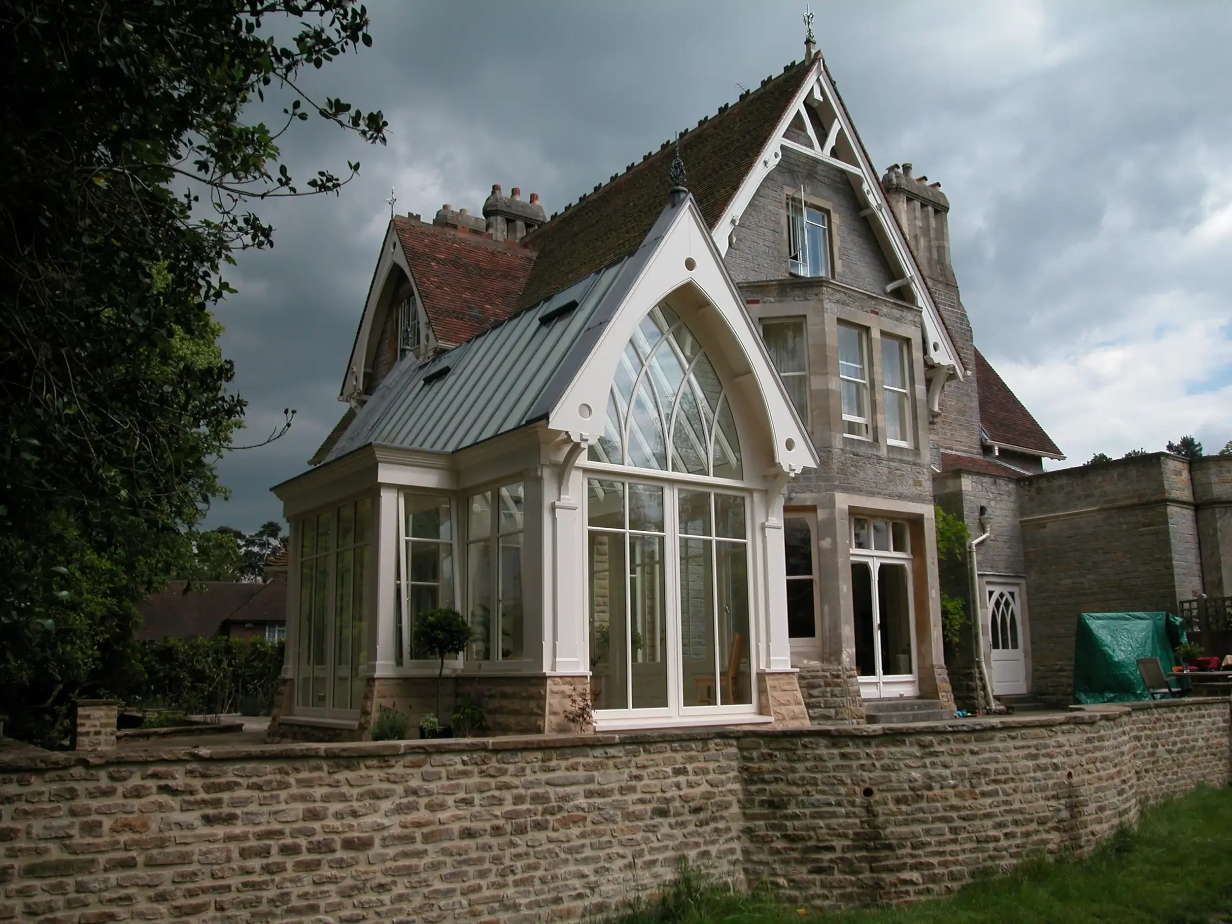 Side angle showing the matched stone walls between the new conservatory and Victorian stone facade.