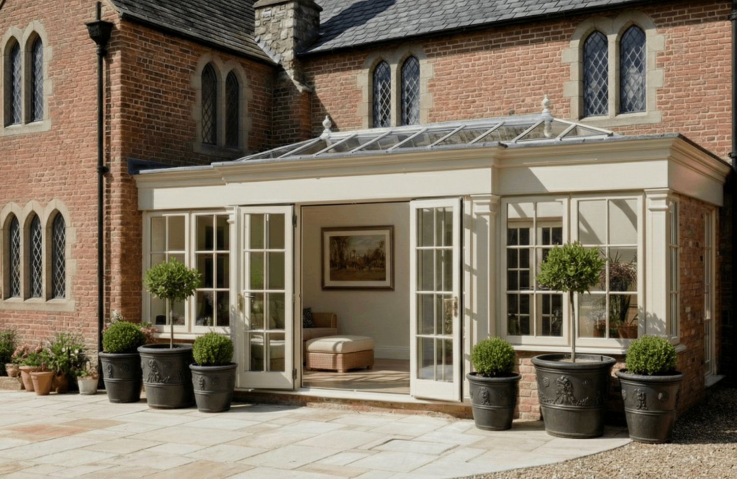 Painted timber orangery with roof lantern attached to a red-brick Gothic Revival house