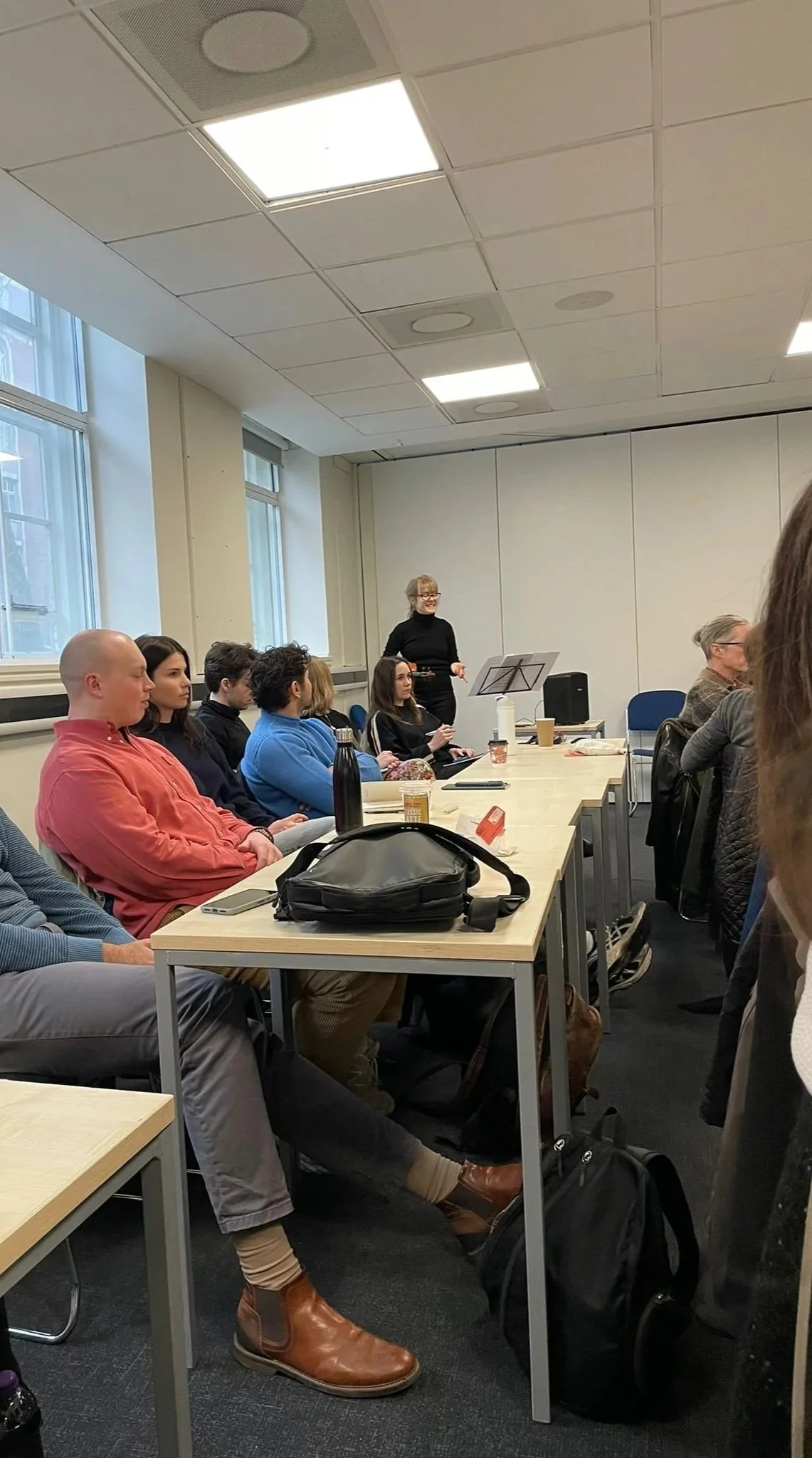 Talia Ramos violinist standing in a lecture room filled with students and giving a lecture and musical intervention exploring psychoanalytic themes through Saint Saens Danse Macabre