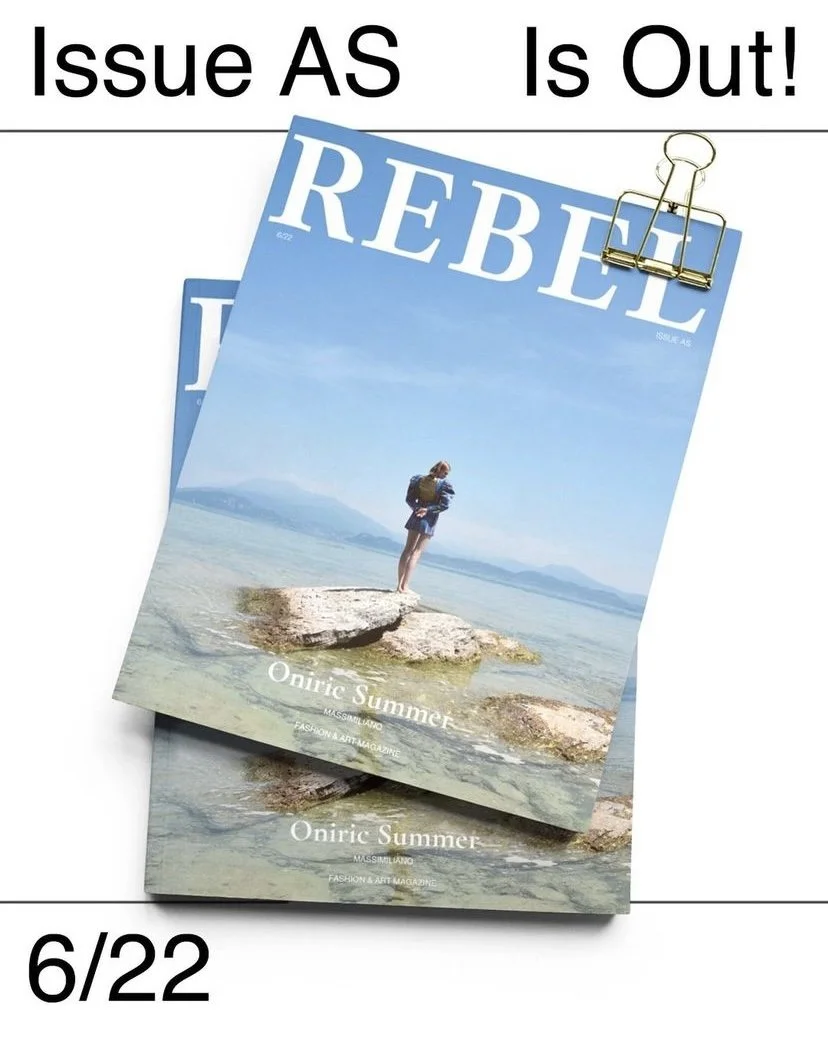 Copertina di una rivista intitolata "REBEL" con un'immagine di una donna sdraiata su una roccia vicino al mare sotto un cielo azzurro.