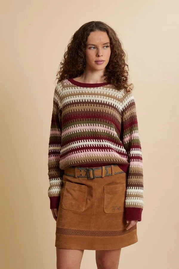 Donna con capelli ricci, maglione a righe multicolore, gonna di pelle marrone e cintura