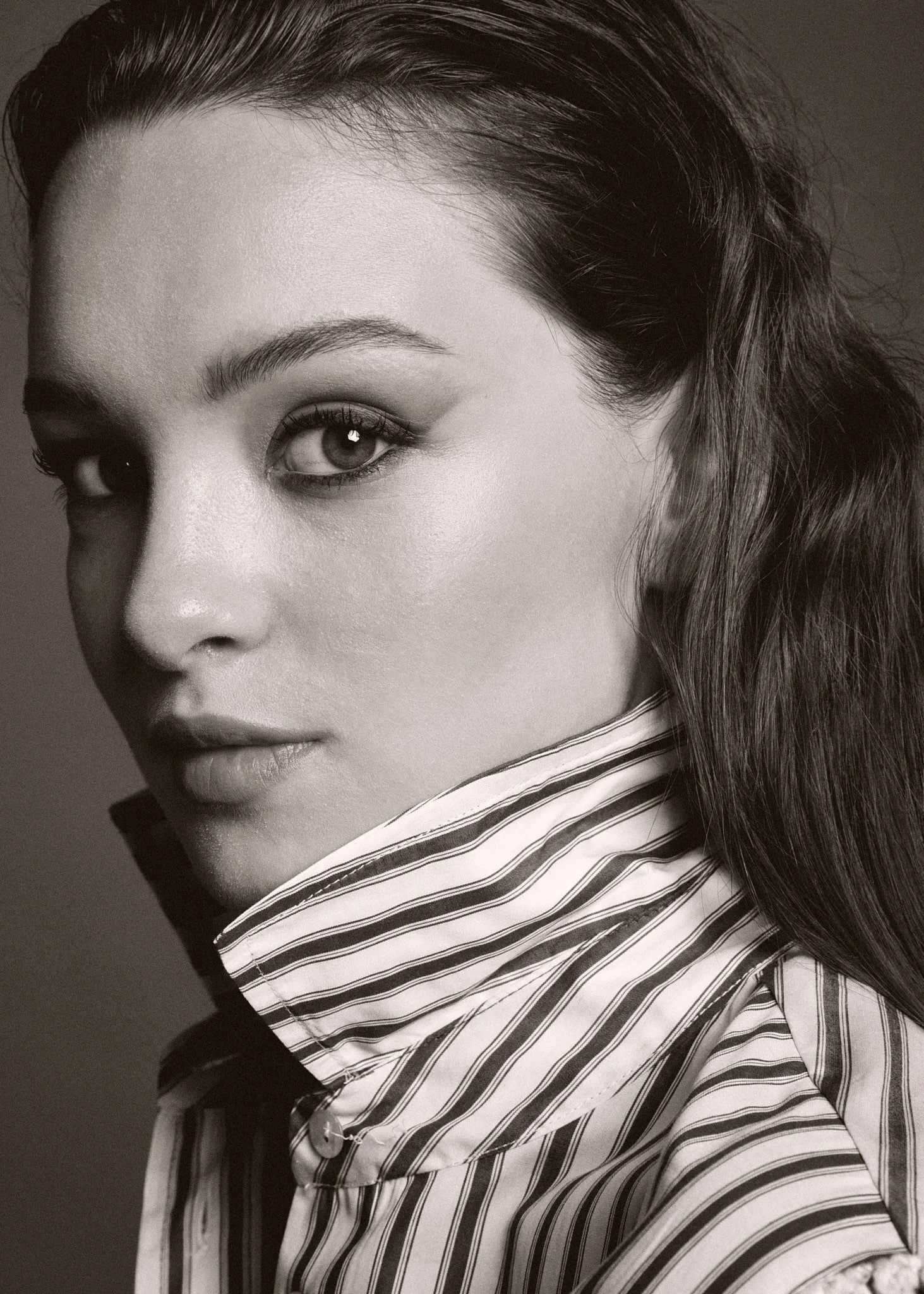Ritratto in bianco e nero di una donna con capelli lunghi e maglietta a righe, che guarda verso sinistra.