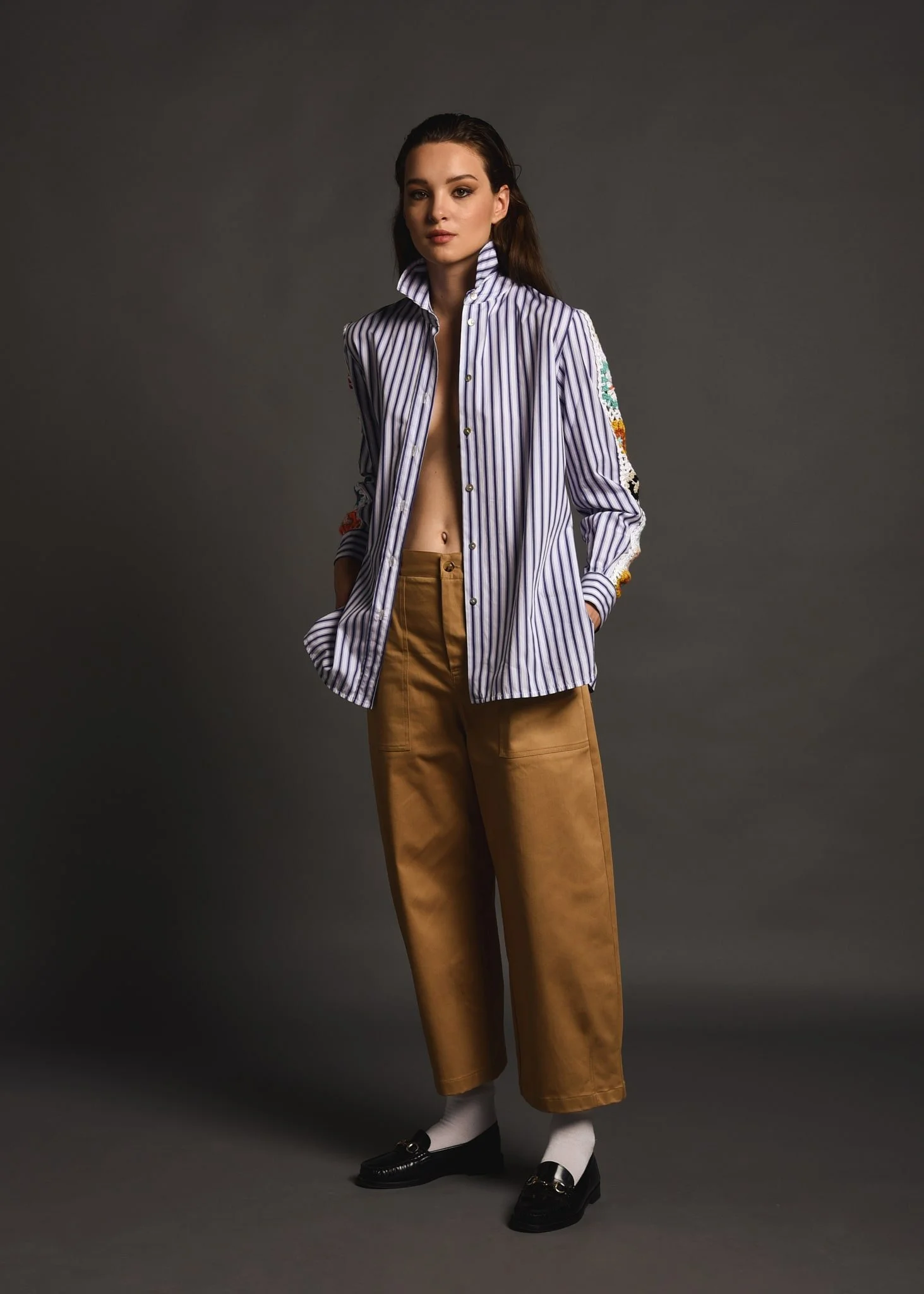 Otra persona con pantalones marroni, camisa de rayas y zapatos negros con calcetines blancos