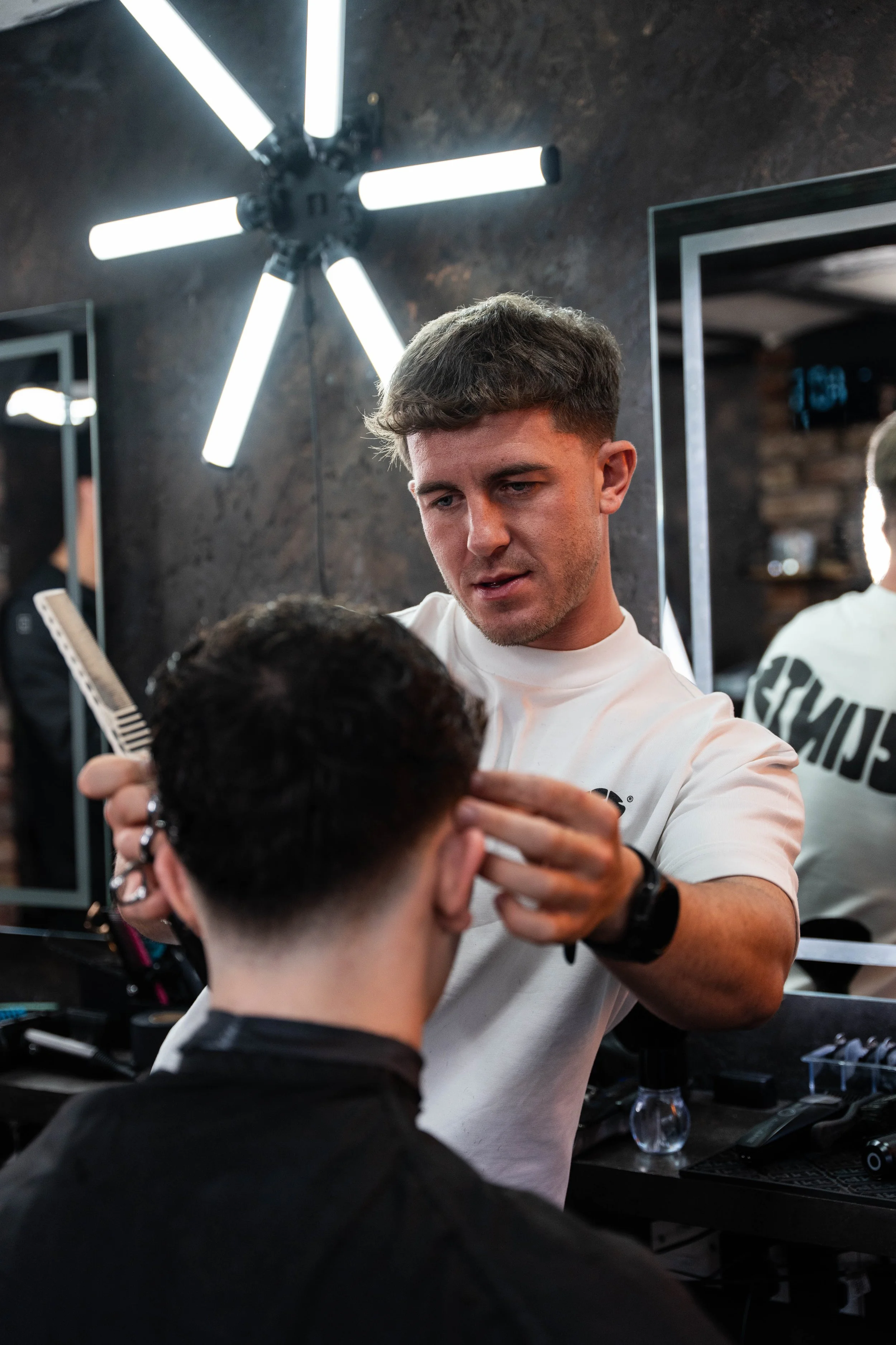 Barber styling a young man's hair in a salon