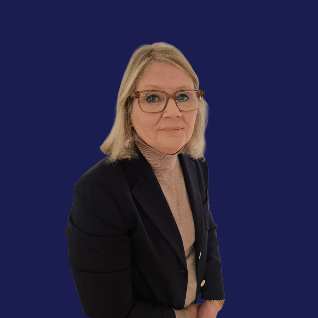 A middle-aged woman with blonde hair wearing glasses, a black blazer, and a beige turtleneck, sitting against a dark blue background.