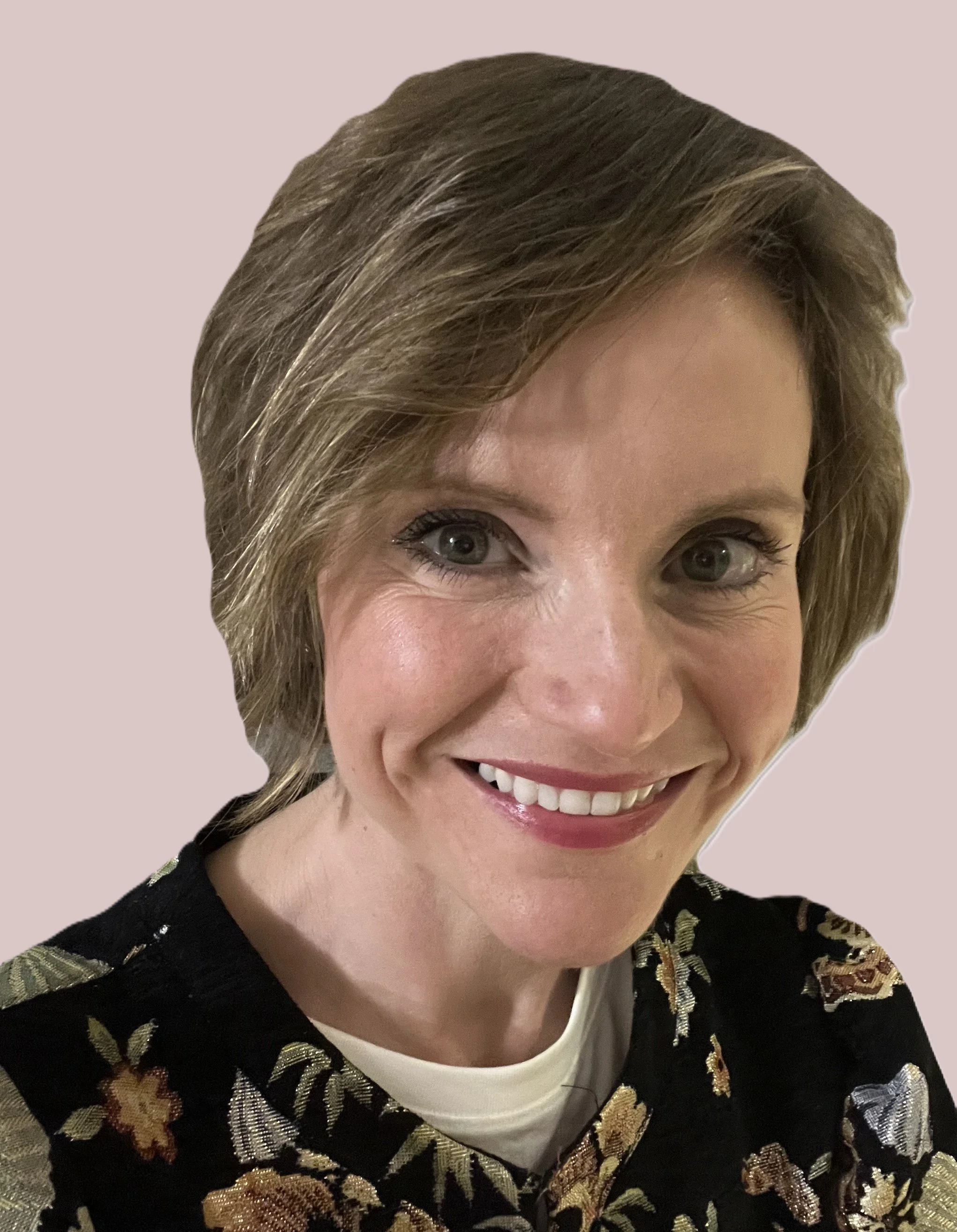 Headshot of Lucy Wood - a woman with short, light brown hair, smiling, wearing a black floral top.