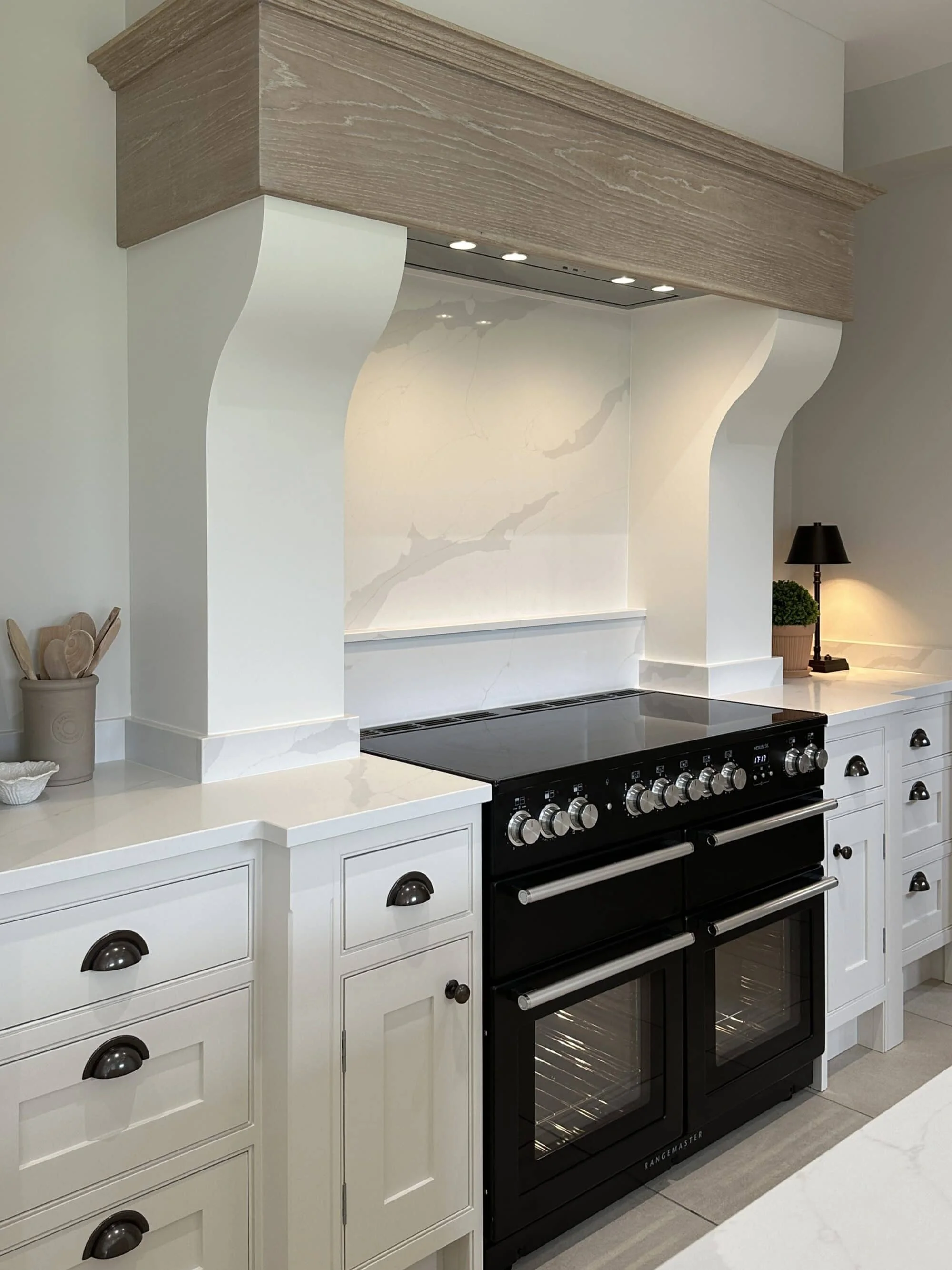 Modern kitchen with white cabinets, black double oven, marble backsplash, and minimalist decor.
