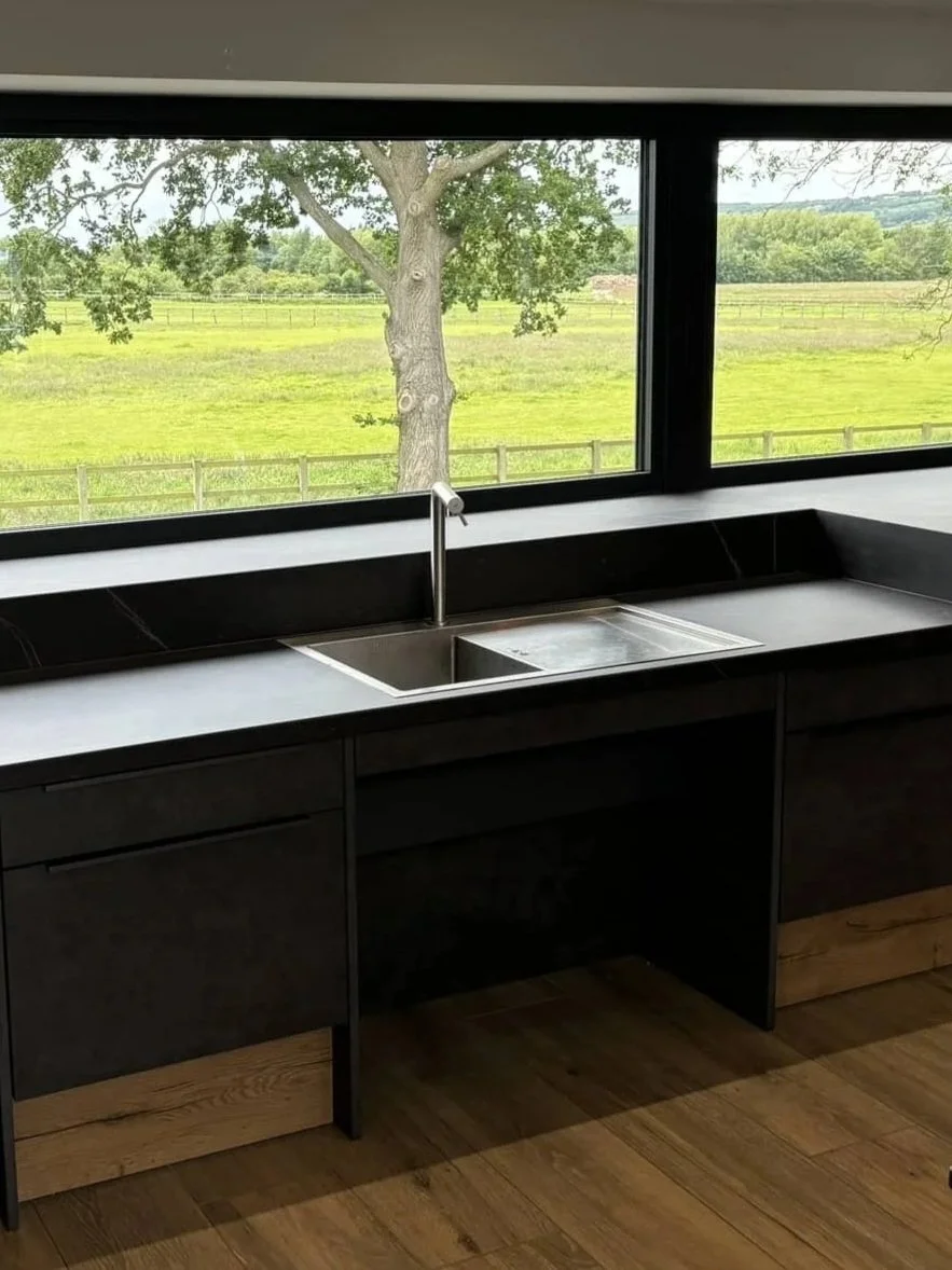 Modern kitchen with a marble backsplash and countertop, stainless steel faucet, and black stovetop.